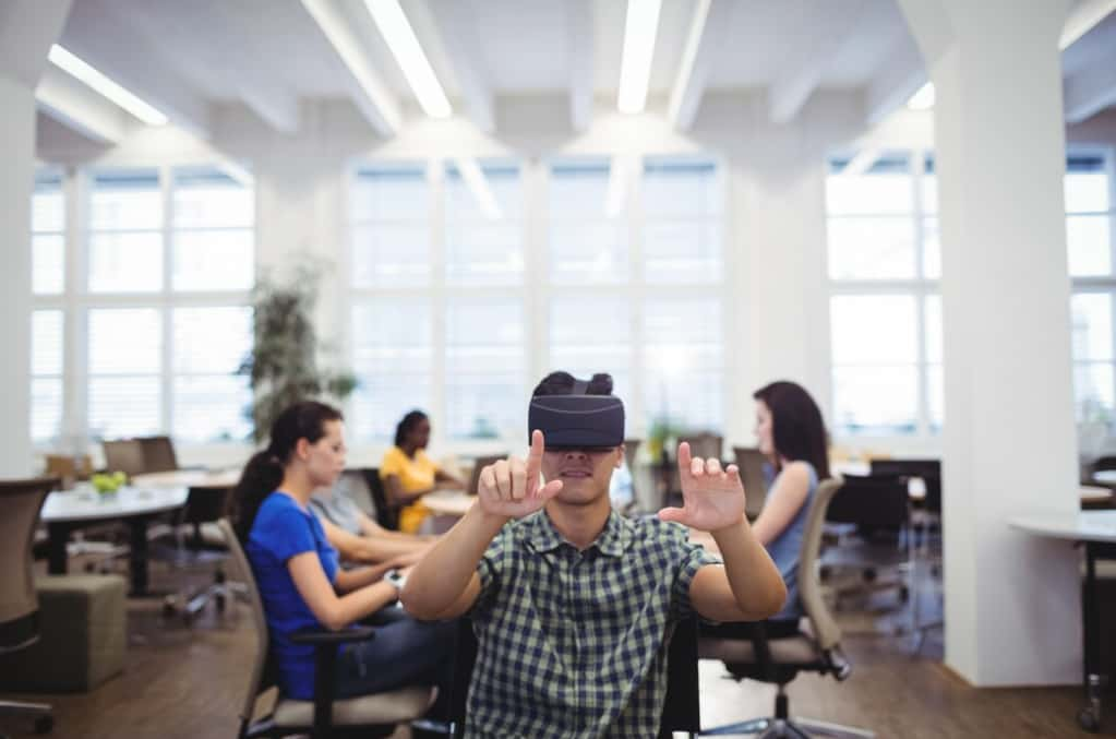 A man in an office wears VR headset, gesturing with hands