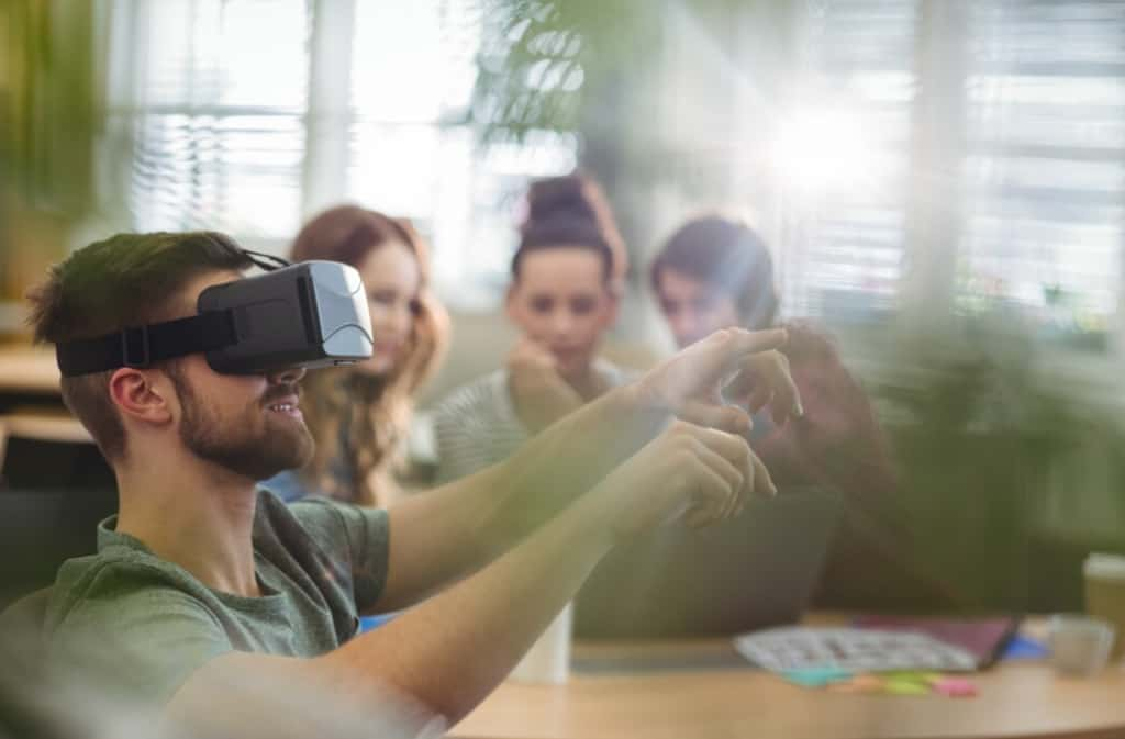 Person with VR gear points in the air, team in the background